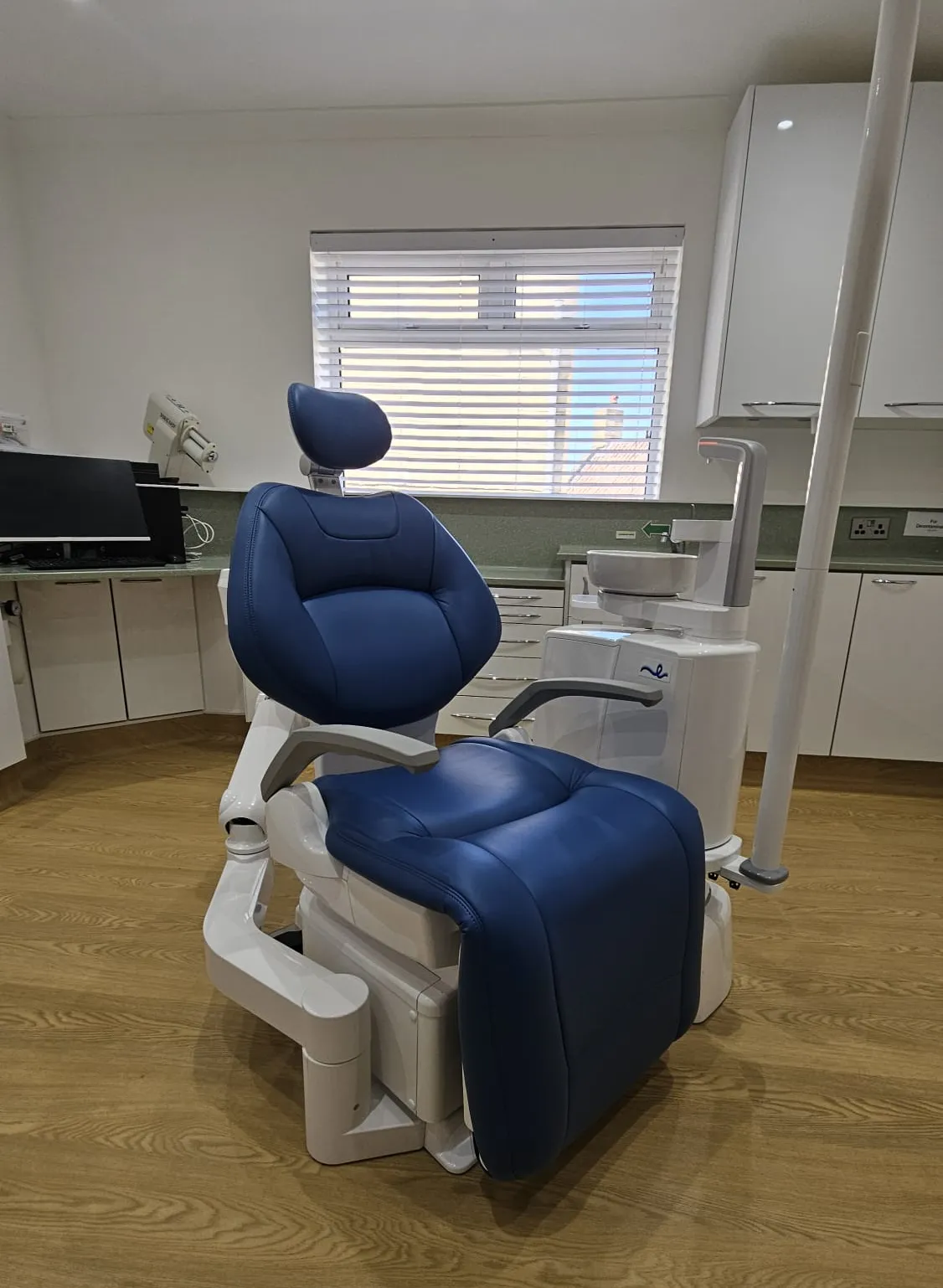 A modern treatment room with a blue dental chair at Paulton Dental